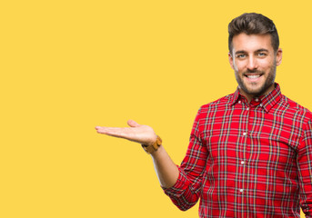Young handsome man over isolated background smiling cheerful presenting and pointing with palm of hand looking at the camera.