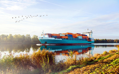 Sonnenaufgang im Herbst am Nord-Ostsee-Kanal in Schleswig-Holstein, Containerschiff auf dem Weg...