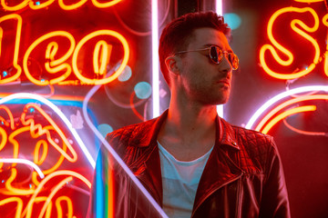 Cinematic portrait of Handsome man with sunglasses and neon lights