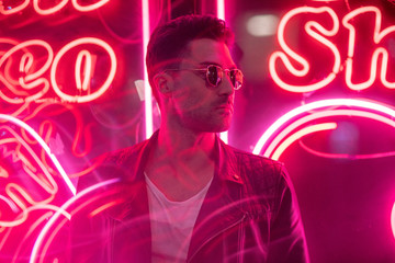 Cinematic portrait of Handsome man with sunglasses and neon lights