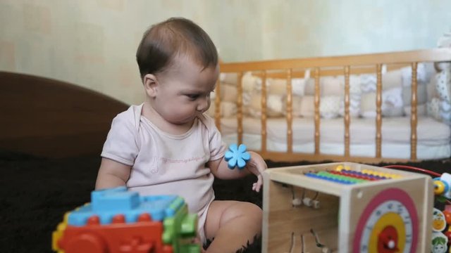Baby girl playing with colorful toys sitting on a bad at home