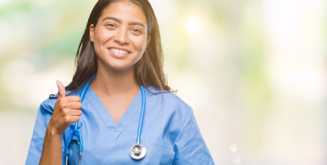 Young arab doctor surgeon woman over isolated background doing happy thumbs up gesture with hand....
