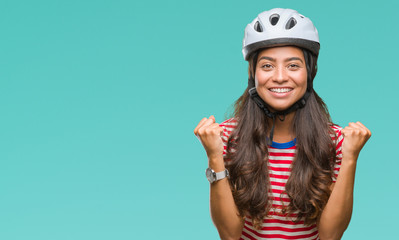 Fototapeta Young arab cyclist woman wearing safety helmet over isolated background celebrating surprised and amazed for success with arms raised and open eyes. Winner concept. obraz
