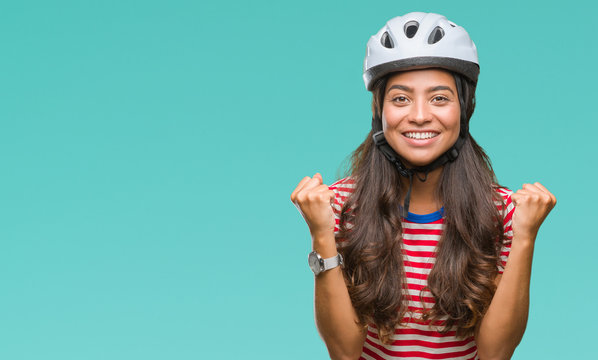 Young arab cyclist woman wearing safety helmet over isolated background celebrating surprised and amazed for success with arms raised and open eyes. Winner concept.