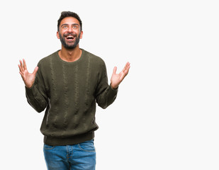 Fototapeta premium Adult hispanic man wearing winter sweater over isolated background celebrating crazy and amazed for success with arms raised and open eyes screaming excited. Winner concept