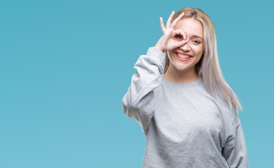 Obraz premium Young blonde woman over isolated background doing ok gesture with hand smiling, eye looking through fingers with happy face.