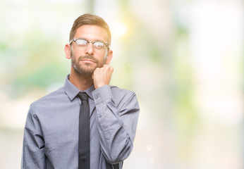 Young handsome business man over isolated background with hand on chin thinking about question, pensive expression. Smiling with thoughtful face. Doubt concept.