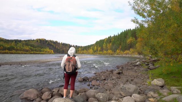 The woman the traveler costs on the bank of the mountain river. Fall.