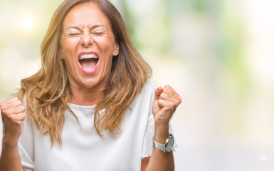 Middle age senior hispanic woman over isolated background celebrating surprised and amazed for success with arms raised and open eyes. Winner concept.