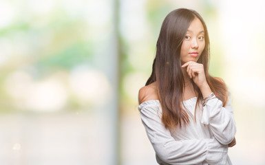 Young asian woman over isolated background looking confident at the camera with smile with crossed arms and hand raised on chin. Thinking positive.