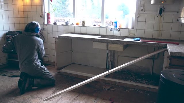 Bearded worker demolishing an old kitchen with a big hammer.