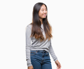 Obraz premium Young asian woman over isolated background looking away to side with smile on face, natural expression. Laughing confident.