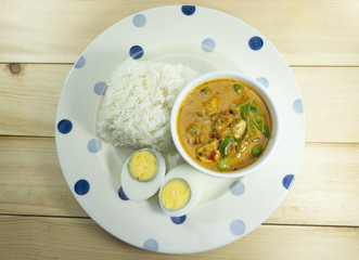 Green Curry Chicken with rice and boiled egg on wooden floor.Thai foods. Close up Top view..