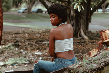 mujer negra afro descendiente sentada en calma sobre metales oxidados