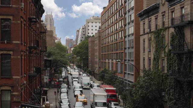 A daytime view of buildings and traffic in a typical Manhattan neighborhood on a summer day.  	