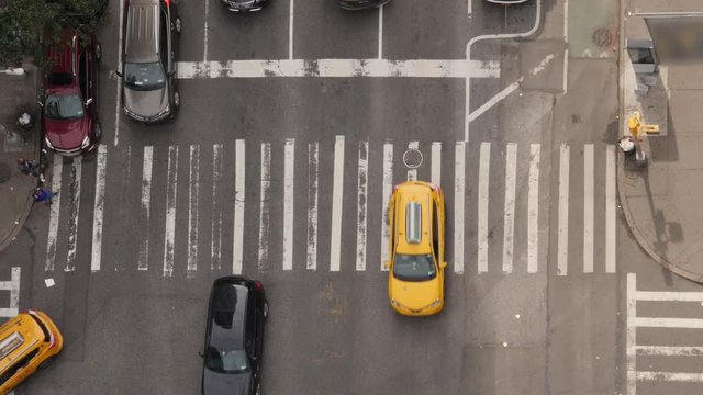 A top down bird's eye view of a typical midtown Manhattan intersection as traffic and pedestrians travel on the streets below.  	