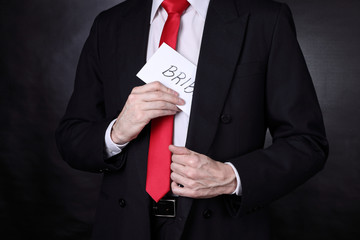 Man in black suit hiding a bribe in his pocket