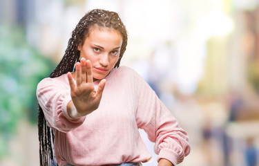 Young braided hair african american girl wearing sweater over isolated background doing stop sing...