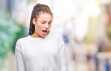 Young braided hair african american girl wearing winter sweater over isolated background winking...