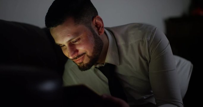 4K Handsome professional man relaxing at home at night & watching movie on computer