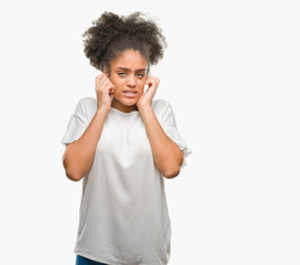 Young afro american woman over isolated background covering ears with fingers with annoyed expression for the noise of loud music. Deaf concept.