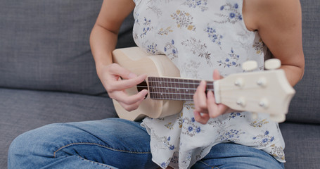 Woman play ukulele at home