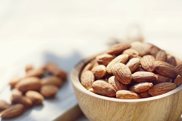 Almond nut in wooden bowl on wood board and table background, copy space