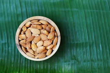 Almond nut in wooden bowl on wood board and table background, copy space