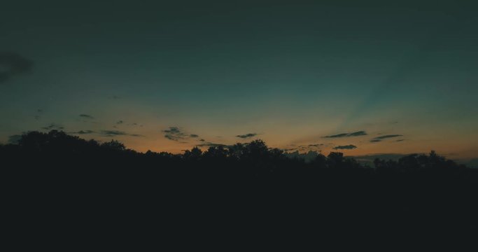 Cinematic sunset slide with drone at the top of a Florida oak forest with sun rays eminating from west and Venus setting.