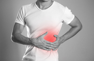 The man is holding his side. Pain in the liver. Cirrhosis. The hearth is highlighted in red. Close up. Isolated background