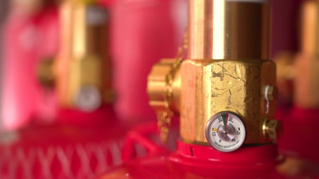 Close up of fire suppression gas cylinder valves and pressure gauge.