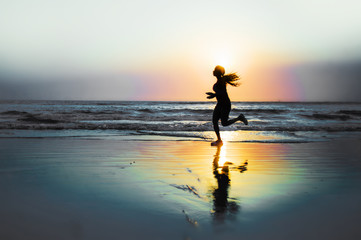 Fototapeta na wymiar silhouette of young happy and attractive African American runner woman exercising in running fitness workout at beautiful beach jogging and enjoying sunset
