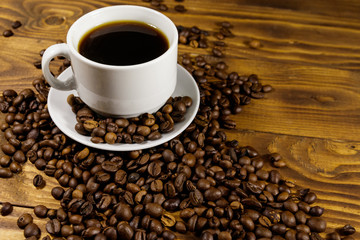 Cup of coffee and roasted coffee beans on wooden table