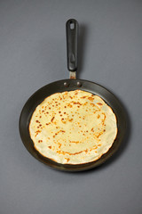Crepe closeup, thin pancake on a frying pan, grey background