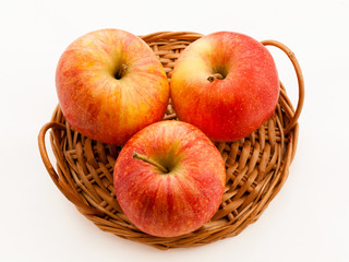 Three red and yellow apples in a basket. Isolated.