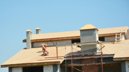 Fototapeta na wymiar Blurred and soft focus on roofer contractors laying asphalt shingles roof.