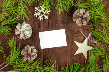 Christmas background with fir tree branches, cones, snow, xmas decorations, a business card, and copy space