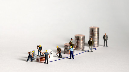 The pile of coins and miniature people. A concept of production and income distribution.