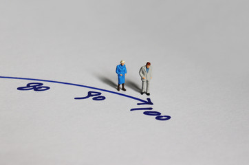 An old couple miniature standing before the number 100.