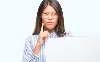 Naklejka premium Young asian woman over isolated background holding blank banner serious face thinking about question, very confused idea