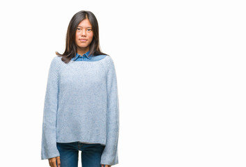 Young asian woman wearing winter sweater over isolated background with serious expression on face. Simple and natural looking at the camera.