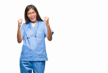 Young asian doctor woman over isolated background very happy and excited doing winner gesture with arms raised, smiling and screaming for success. Celebration concept.