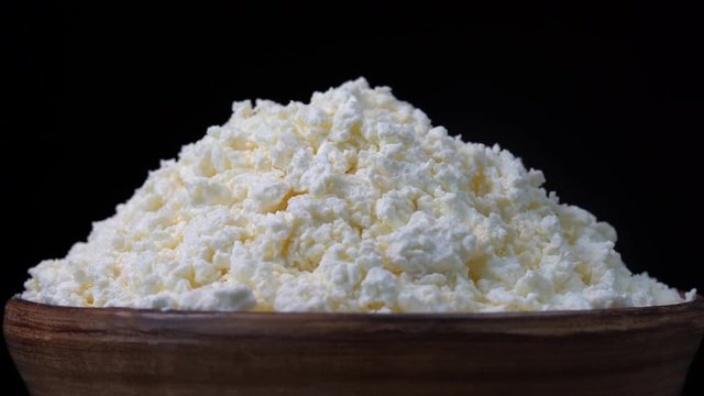 White cottage cheese in black background. Rotates bowl with fresh cottage cheese. Close up. Nourishing breakfast