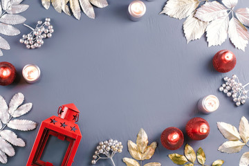 Winter concept flat lay with golden and silver leaves and red candles with snow falling. Christmas frame background