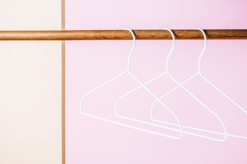 three white empty hangers for shopping on pink