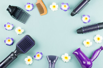 Hairdressing tools with flowers on blue wooden background