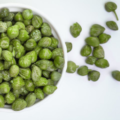 Capers in white bowl on white background