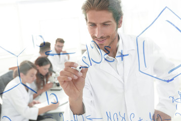 smiling scientist records data on a glass Board.