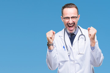 Middle age senior hoary doctor man wearing medical uniform isolated background celebrating surprised and amazed for success with arms raised and open eyes. Winner