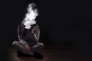 girl on a black background smoking a vape (electronic cigarette) image with space for text